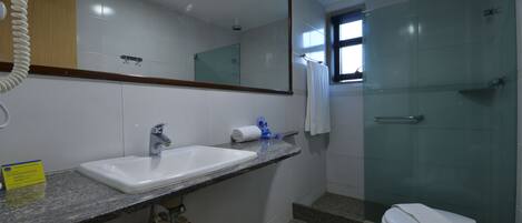 Un baño con lavamanos, espejo y cabina de ducha de vidrio.