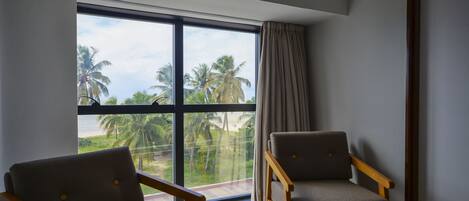 Una habitación con dos sillas de madera y un ventanal con vistas a un balcón con palmeras.