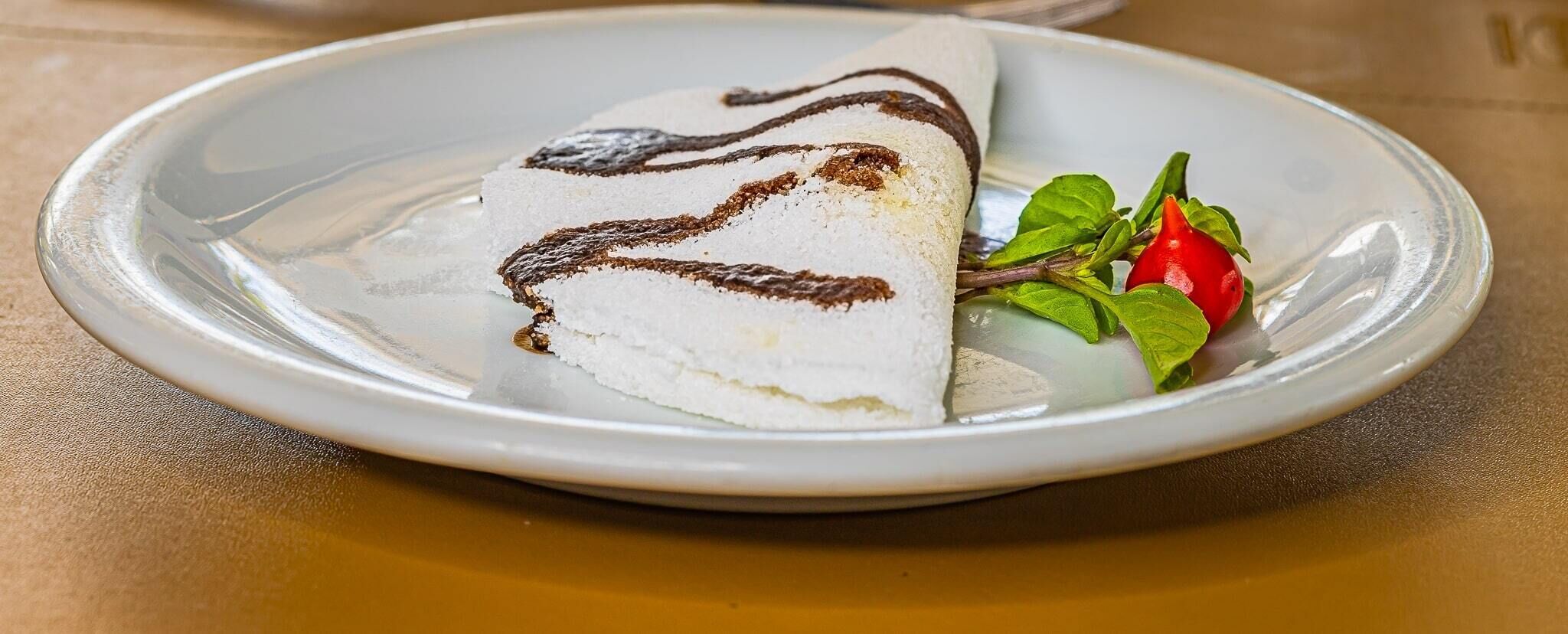 A dessert on a plate with chocolate drizzle and a small garnish.