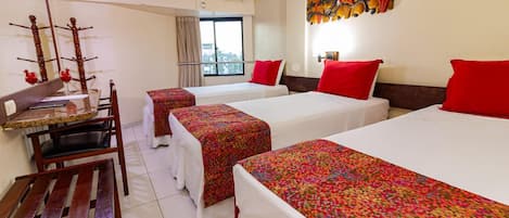 A hotel room with two beds, a desk, and a chair. There is a window with a view of the city.