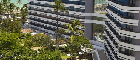 Um hotel moderno com várias varandas, área de piscina e vista para o oceano.