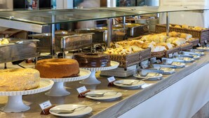 A buffet with various desserts and food items displayed on trays and plates. - Maceio Atlantic Suites (Maceió)