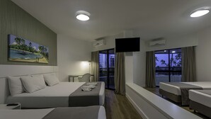 A hotel room with two beds, a TV, and a balcony with a view of palm trees. - Maceio Atlantic Suites (Maceió)