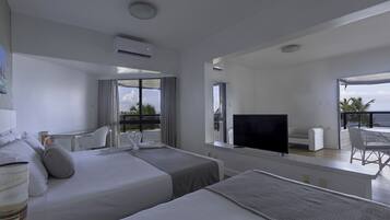 Quarto de hotel moderno com duas camas, uma TV e uma varanda com vista.