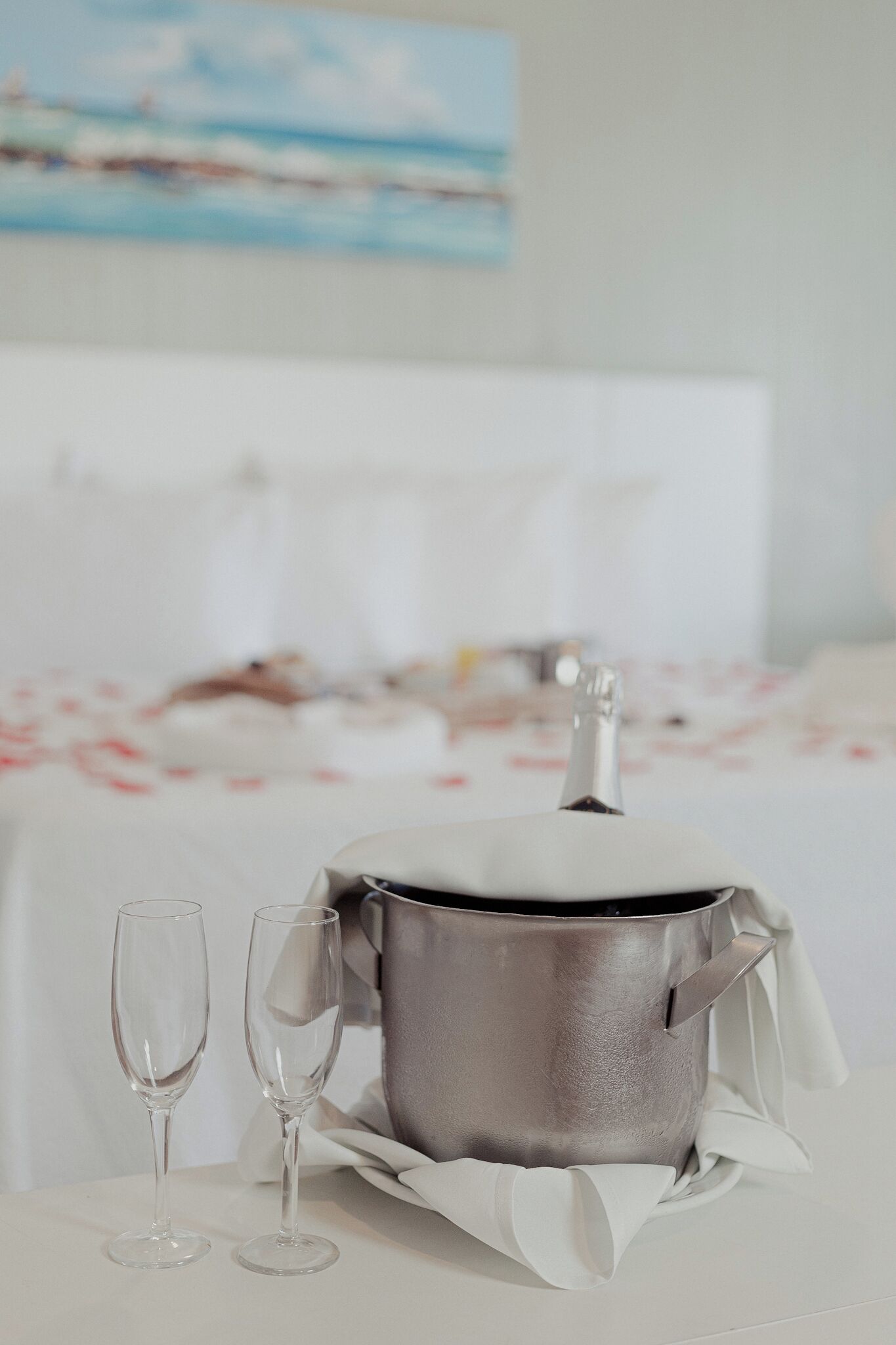 A metallic pot with a lid on a table, accompanied by two clear wine glasses.