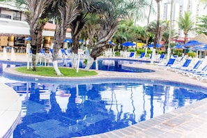 Relax by the pool surrounded by palm trees and lounge chairs.