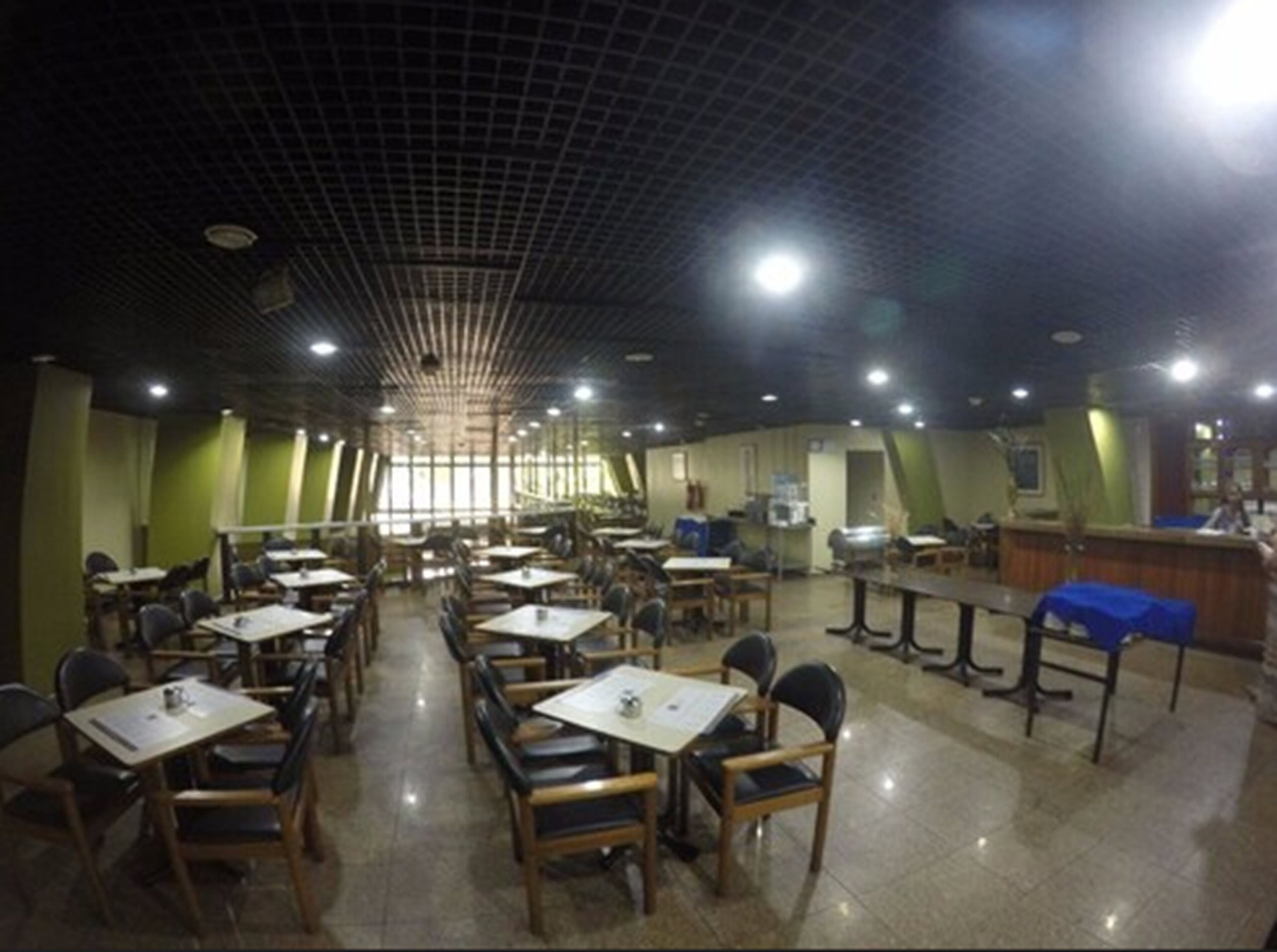A spacious dining area with multiple tables and chairs, a counter, and a tiled floor.