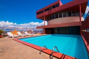 A swimming pool with lounge chairs and a red building with large windows. - GoldMen Business Manaus - Taj Mahal (Manaus)