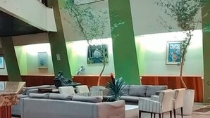 A spacious lobby with a high ceiling, green accent walls, and a seating area with sofas and chairs. - GoldMen Business Manaus - Taj Mahal (Manaus)