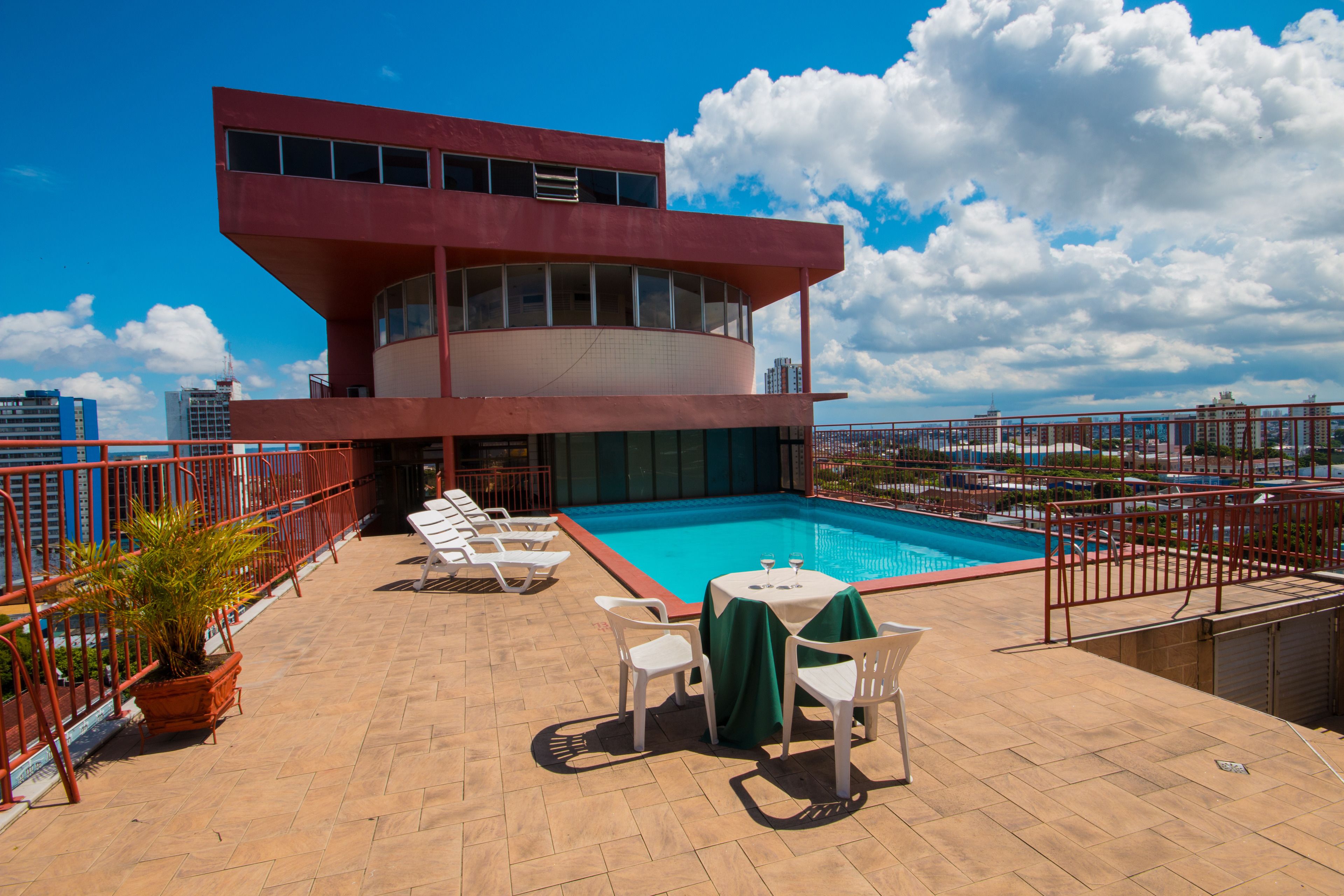 A rooftop pool area with a pool, lounge chairs, and a table with a green tablecloth.