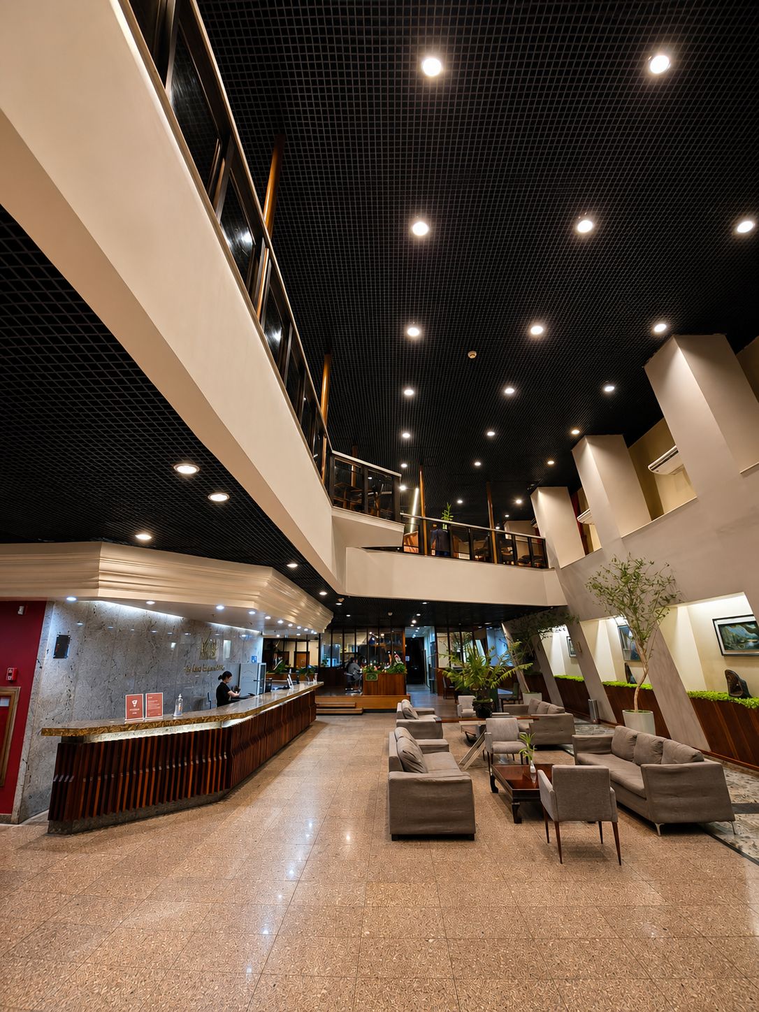 A spacious lobby with a reception desk, seating area, and a mezzanine level.