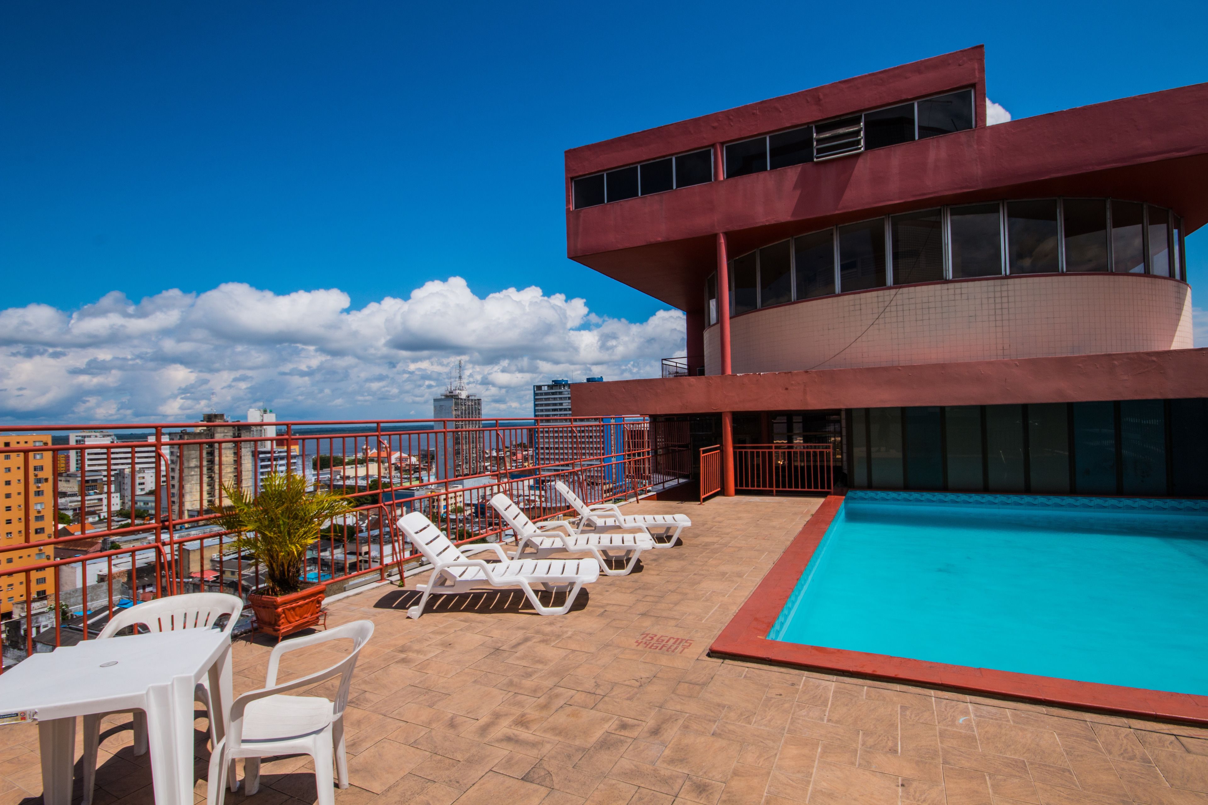 A rooftop pool area with lounge chairs and a view of the city skyline.