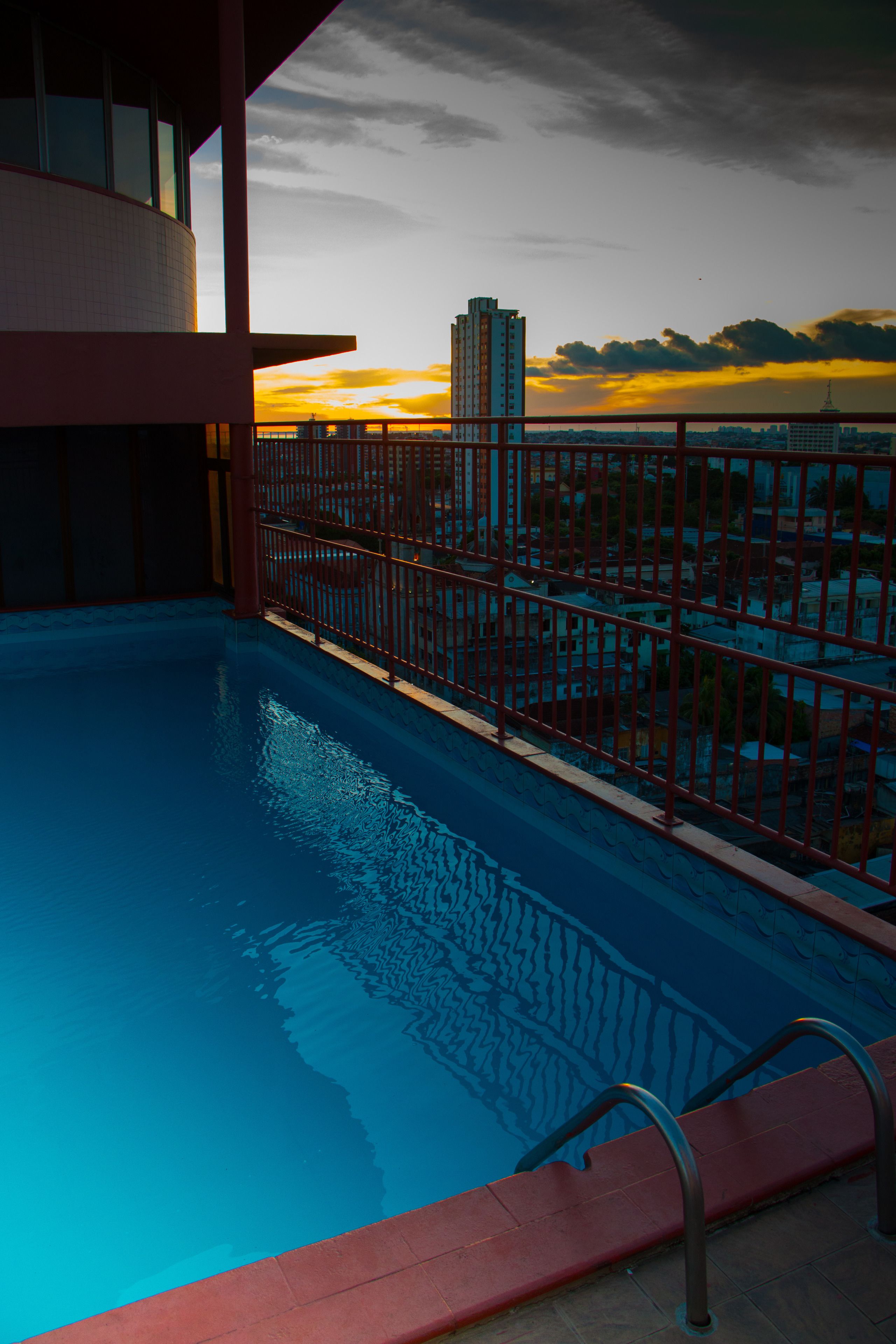 Una piscina con vistas a un paisaje urbano al atardecer.