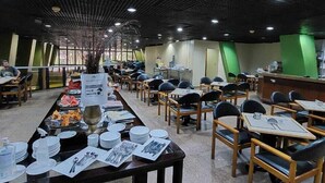 A spacious dining area with tables and chairs, a buffet setup, and a green accent wall. - GoldMen Business Manaus - Taj Mahal (Manaus)