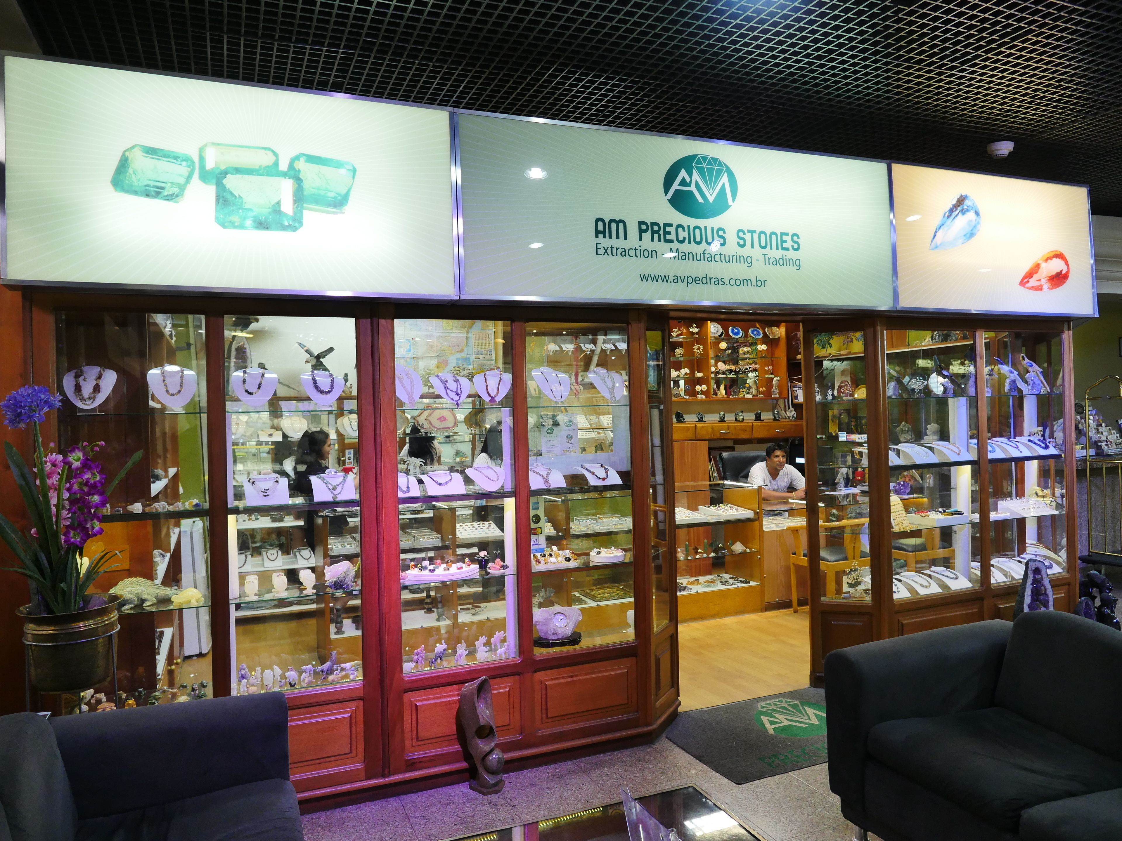 A jewelry store with glass display cases and a sign reading "AM PRECIOUS STONES".