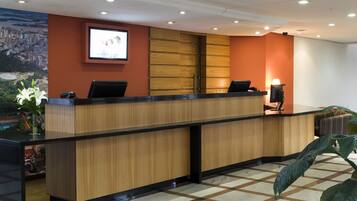 A reception desk with a wooden finish, a large screen above it, and a check-in counter.