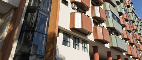 Un edificio de gran altura con varios balcones, ventanas amplias y un diseño arquitectónico moderno.