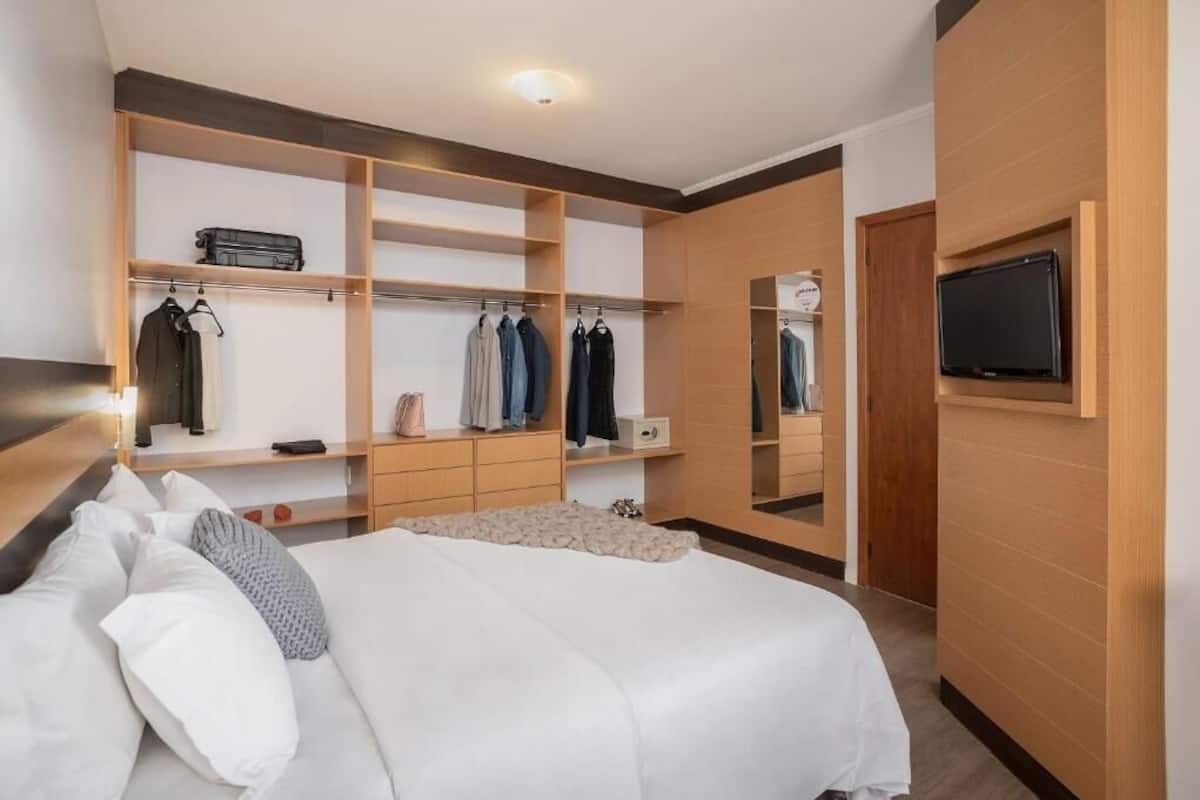 Ein modernes Schlafzimmer mit einem großen Bett, einem Einbauschrank und einem an der Wand befestigten Fernseher.