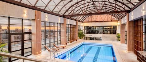 Una piscina techada, sillones reclinables de piscina