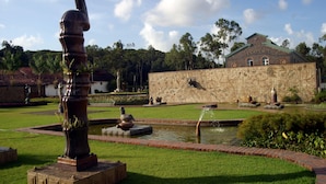 A garden with a bronze sculpture, a fountain, and a building labeled "Academia" in the background. - Internacional Palace Hotel (Recife)