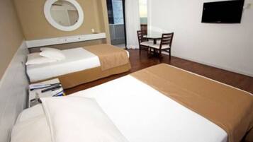 A hotel room with two beds, a round mirror, a small table, and a TV on the wall.