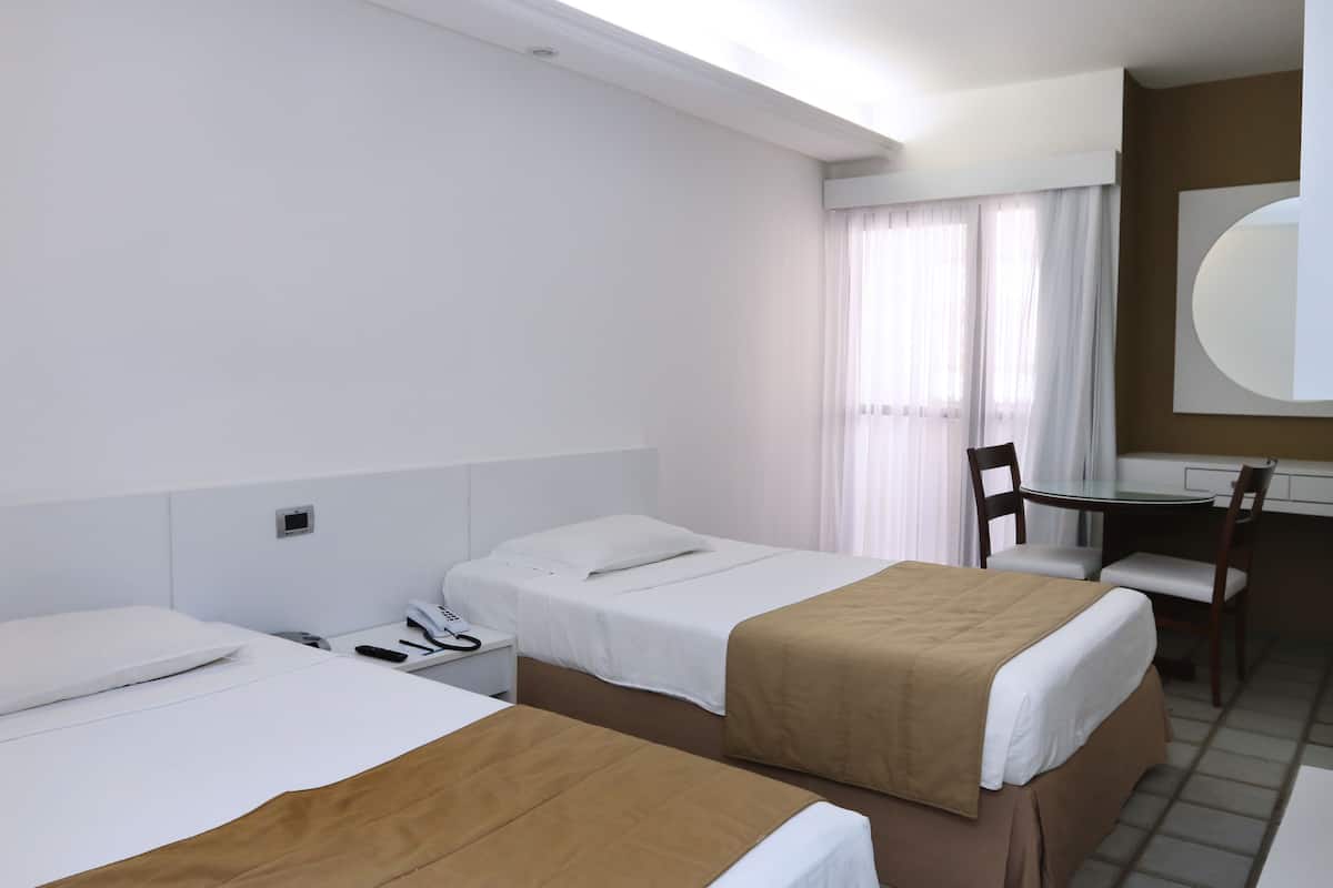 Una habitación de hotel con dos camas, un escritorio y una silla.
