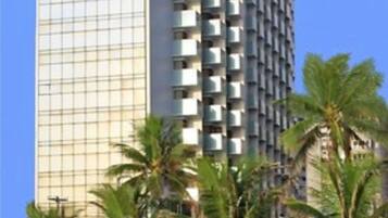 A tall, modern hotel with a glass facade and multiple balconies.