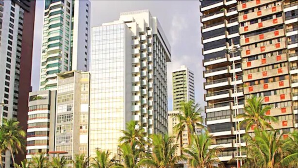 A beachfront hotel with high-rise buildings, palm trees, and a sandy beach. - Internacional Palace Hotel (Recife)