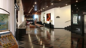A spacious lobby with a high ceiling, a map display, a lion statue, and a staircase leading to an upper level. - Internacional Palace Hotel (Recife)