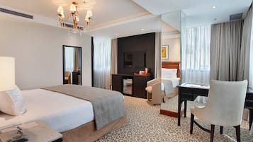 A hotel room with a large bed, a desk with a chair, a television, and a mirror.