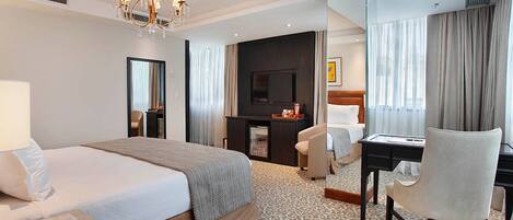 A hotel room with a large bed, a desk with a chair, a television, and a mirror.