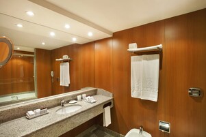 A hotel bathroom with wooden paneling, a double sink, a mirror, and a towel rack.