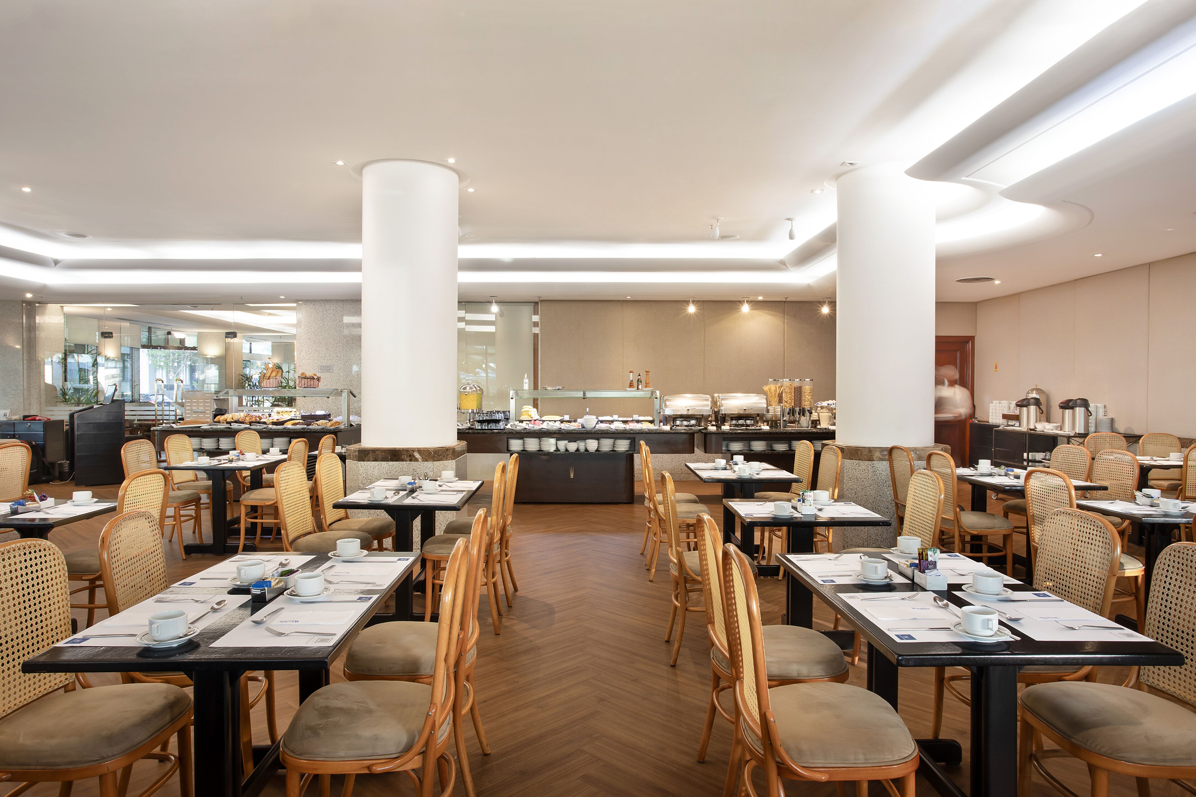 Ein geräumiger Speisesaal mit mehreren Tischen und Stühlen, einer Buffettheke und einem modernen Interieur.