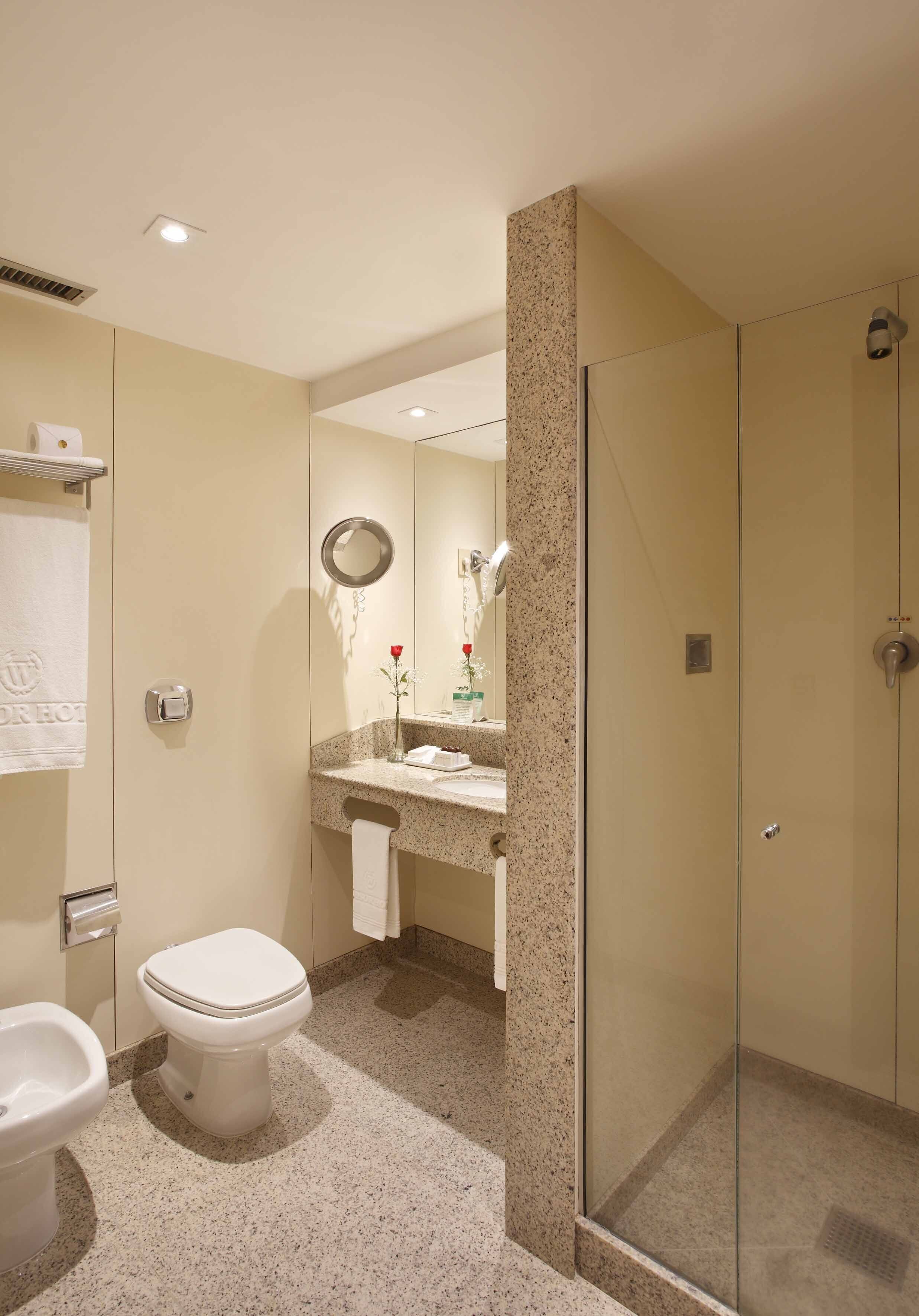 Une salle de bain moderne équipée de toilettes, d’un bidet et d’une douche à parois de verre.