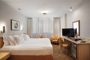 Une chambre d’hôtel comprenant un lit, un bureau avec une télévision, une chaise et un mini-bar.