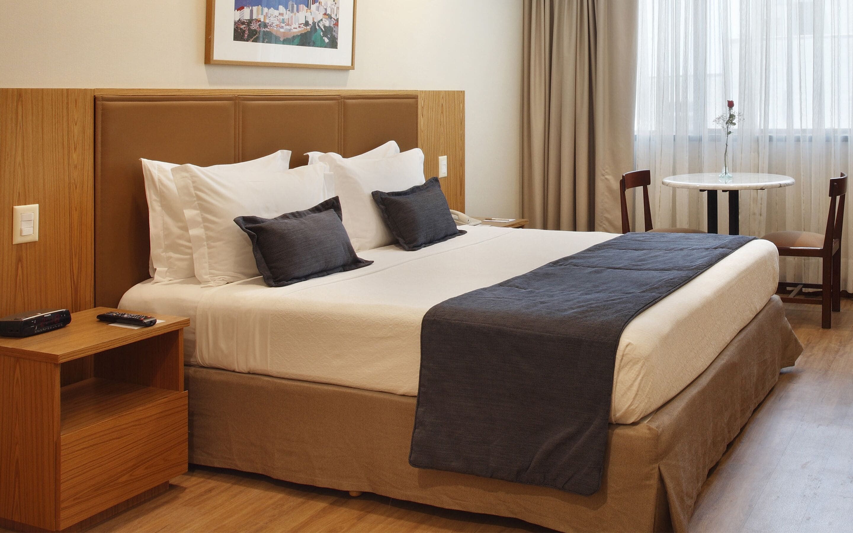 Une chambre d’hôtel avec un grand lit, une table de chevet, une petite table avec un vase et une chaise.