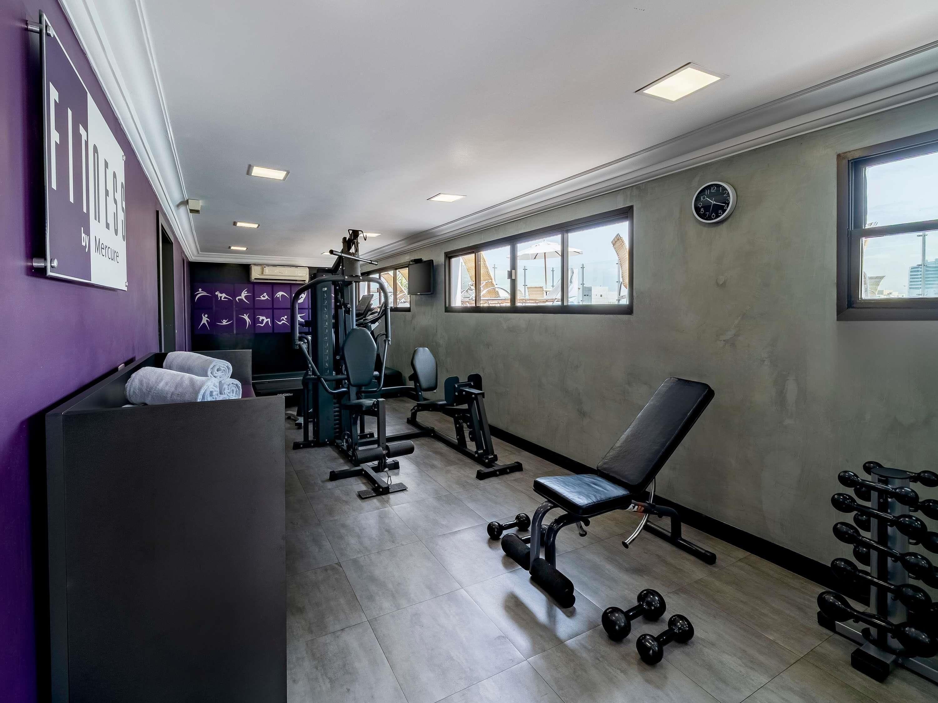 A gym with exercise equipment, a bench, and a wall clock.