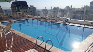 Una piscina al aire libre, sombrillas, sillones reclinables de piscina