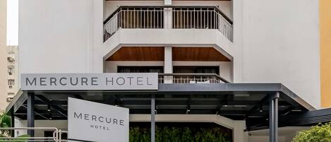 L’entrée d’un hôtel, avec une enseigne indiquant « Hôtel Mercure » et des panneaux de signalisation indiquant « Parking » et « Restaurant ».