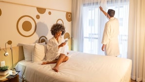 A hotel room with a bed, a bedside table with a cup and a plant, and a window with curtains. - Mercure Sao Paulo Alamedas (São Paulo)