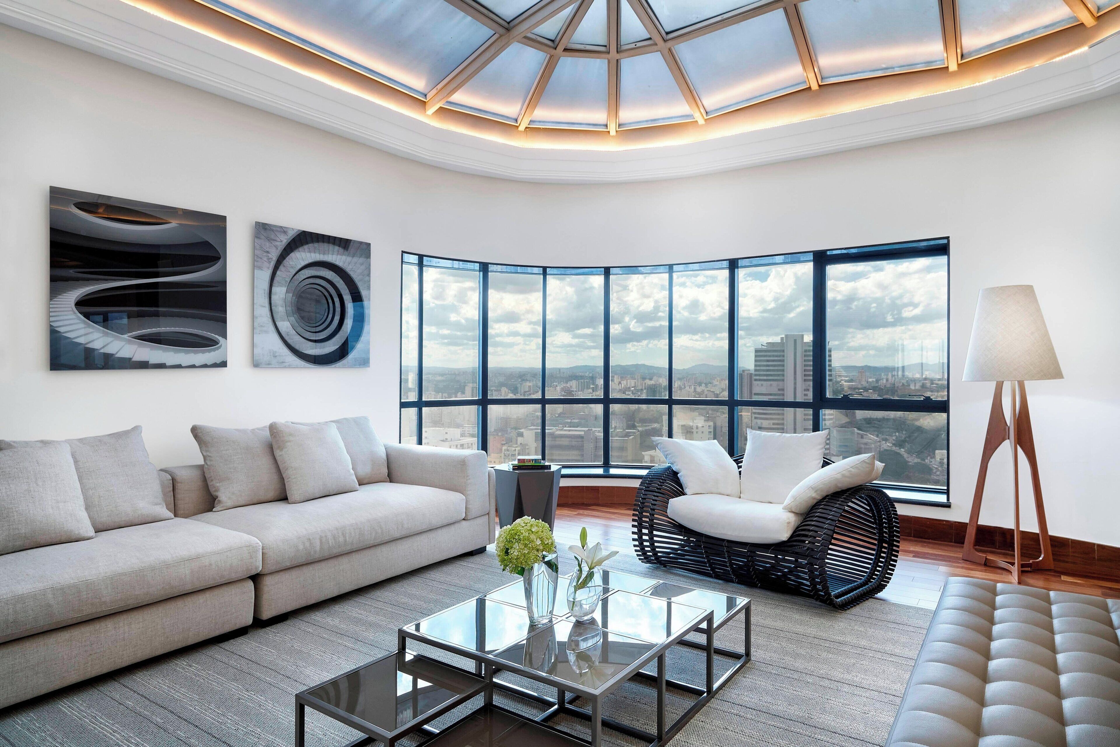 Una sala de estar moderna con un ventanal grande, un sofá, una mesa de centro y una silla.
