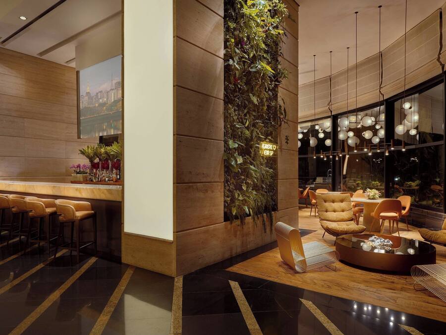 Un lobby moderno con zona de bar, asientos y un amplio ventanal con vistas a la ciudad.