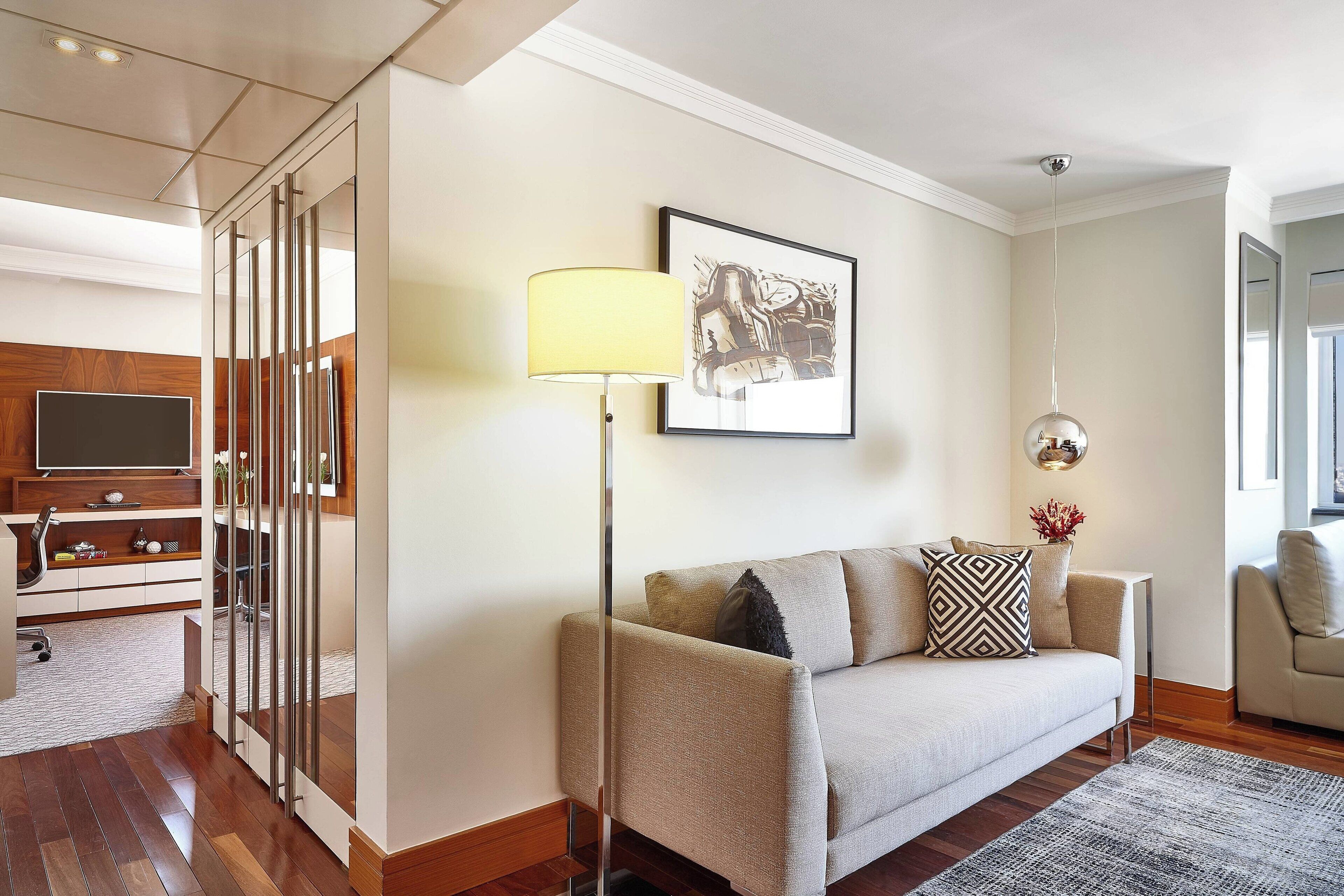 A modern living room with a sofa, a floor lamp, a framed picture, and a TV.
