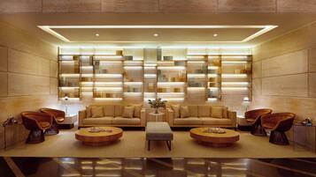 Relax in a stylish lobby with sofas, side tables, and lamps, set amidst a geometric pattern of recessed lighting.