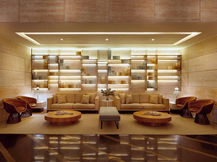 A modern lobby with a central seating area, a large illuminated wall, and a polished floor.