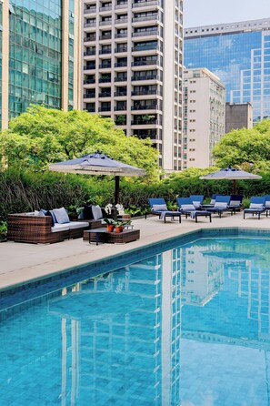 Een buitenzwembad, parasols bij het zwembad en ligstoelen