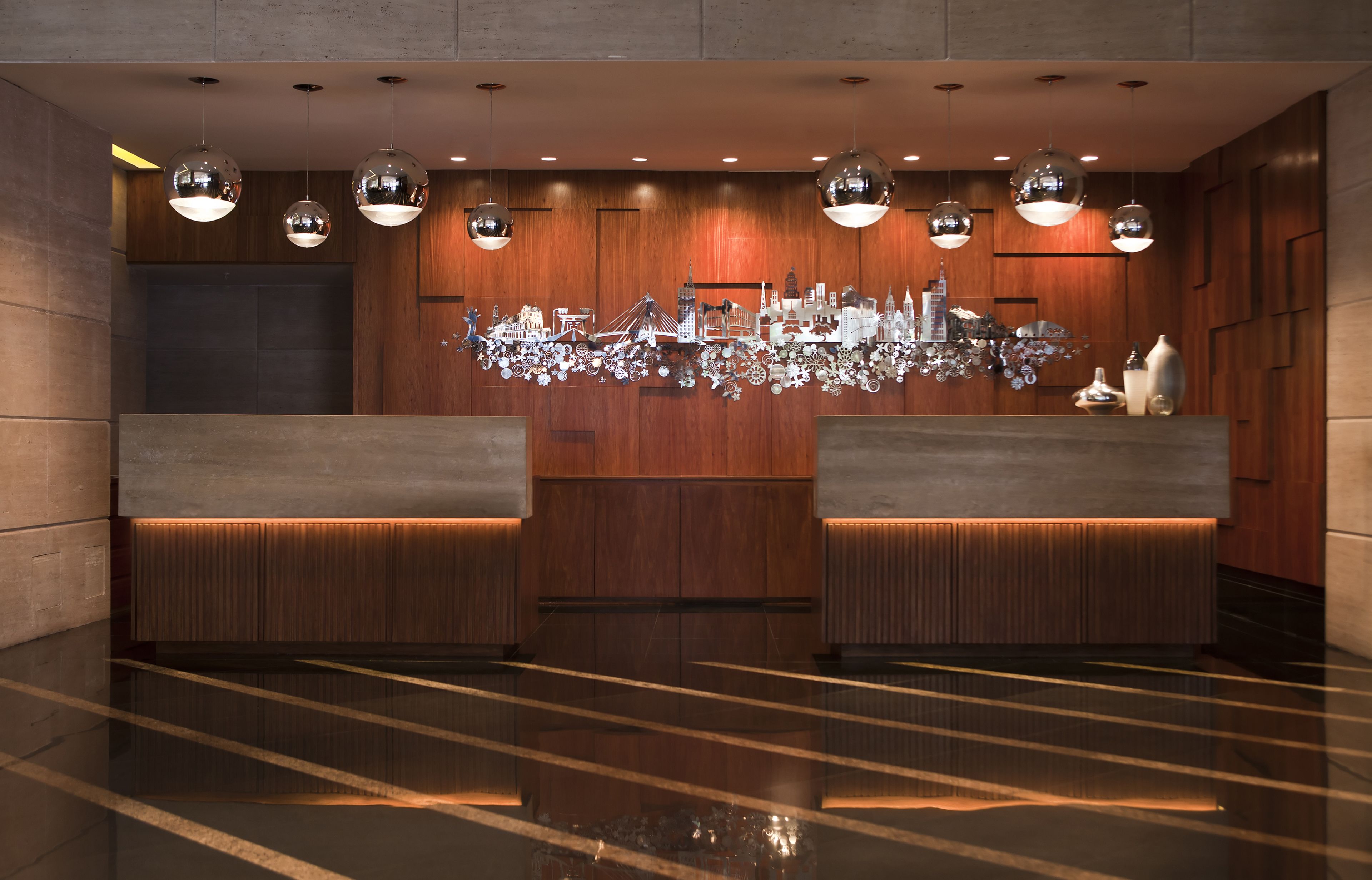 A modern reception area with a wooden panel wall, a reflective sculpture, and a polished floor.