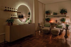 Una sala de estar moderna con suelo de madera, un espejo redondo, un sofá y varias macetas con plantas.