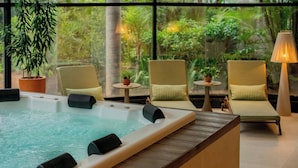 A spa area with a hot tub, lounge chairs, and a view of a lush garden through large windows. - Renaissance São Paulo Hotel (São Paulo)
