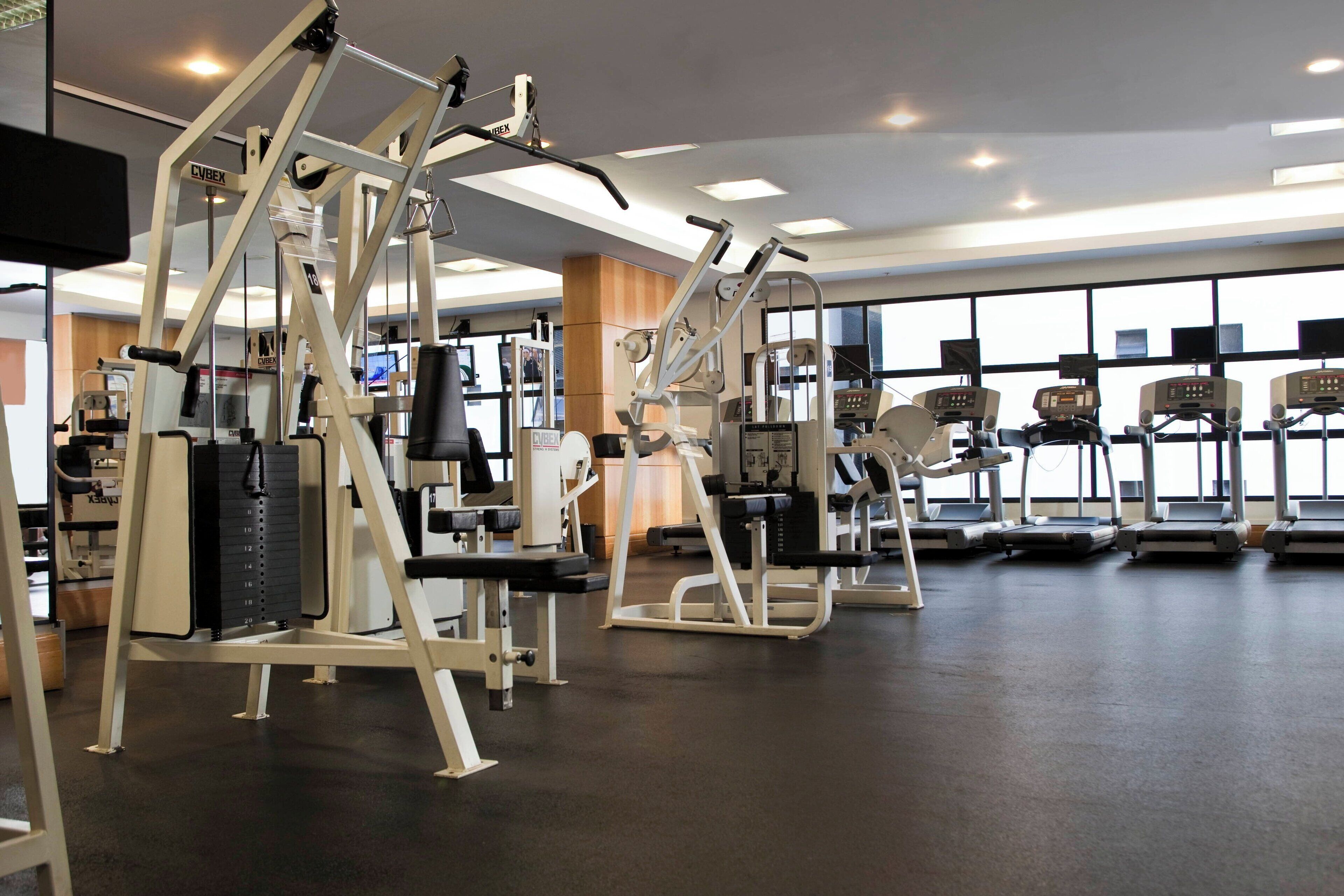 Ein Fitnessstudio mit verschiedenen Trainingsgeräten, großen Fenstern und einem klaren, modernen Design.